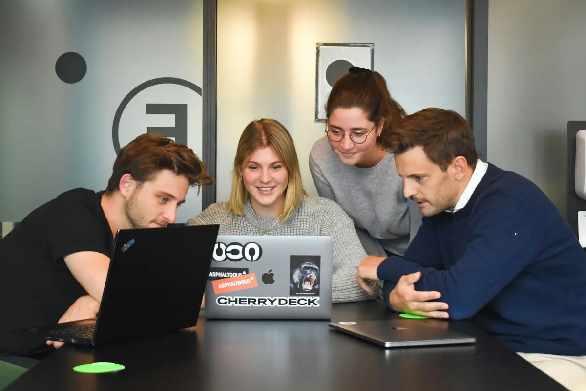 Four colleagues reviewing a process on a laptop