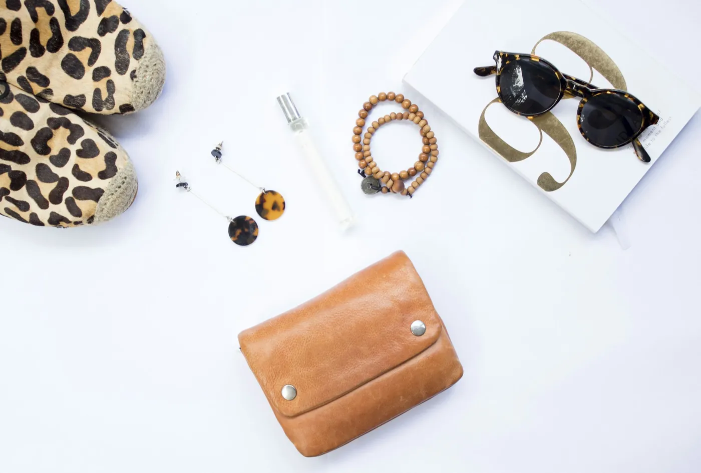 A flat lay of leopard-print shoes, a leather wallet, sunglasses and accessories