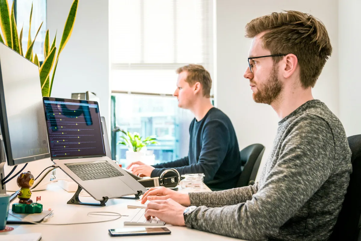 Two engineers reviewing an AI system on a laptop