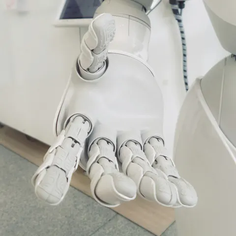 Close-up of a white robotic hand resting on a desk