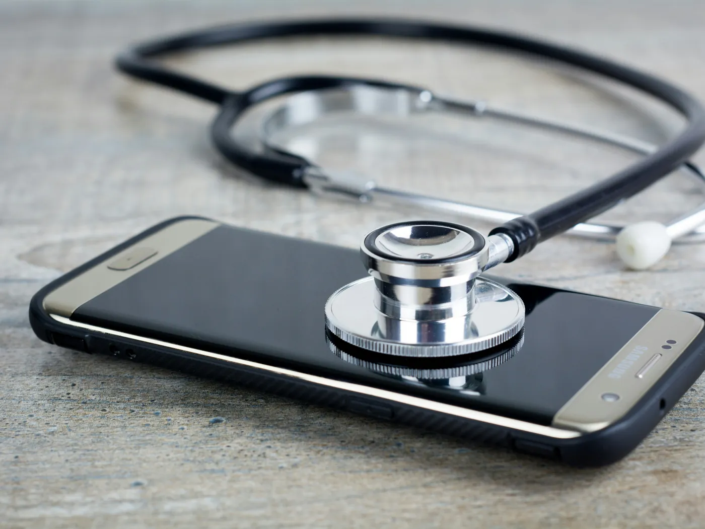 A smartphone on a table with a stethoscope resting on its screen