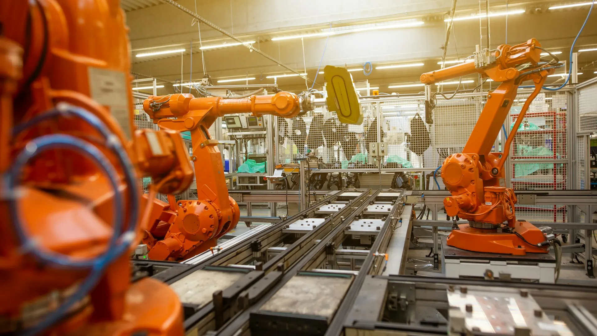Orange robotic arms working along an automated production line