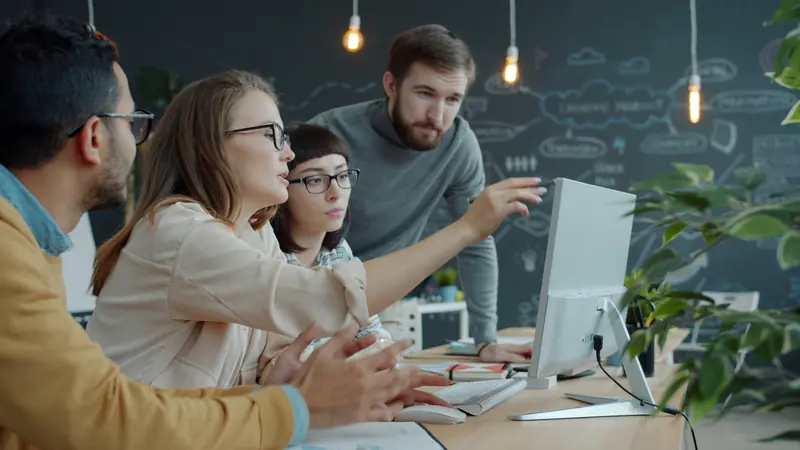Colleagues gathered around a monitor reviewing an internal tool