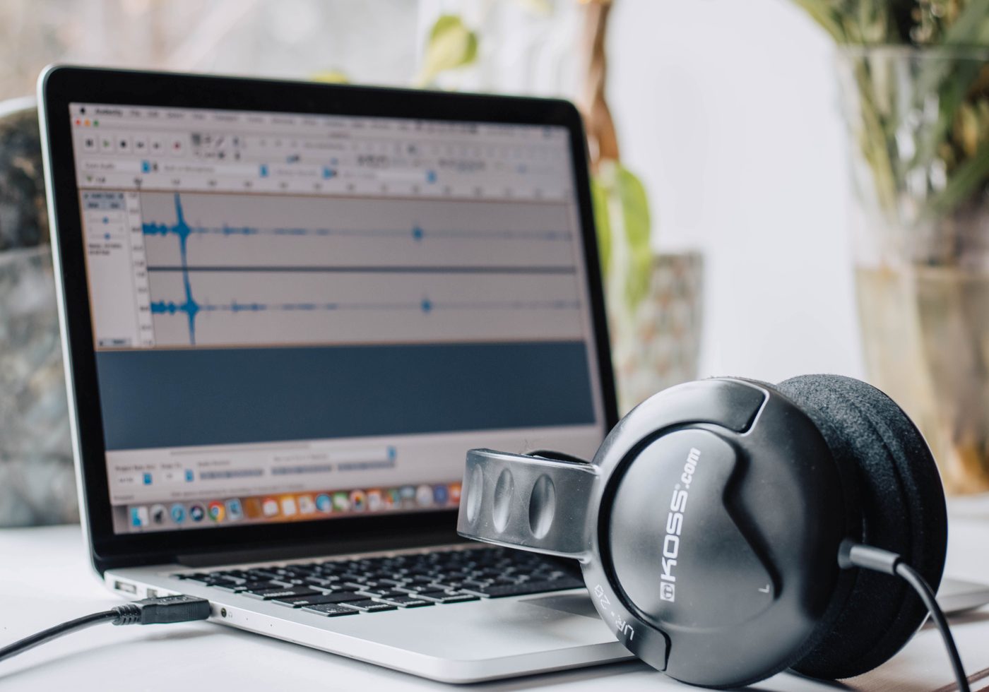 Audio waveform open in an editor on a laptop with studio headphones beside it