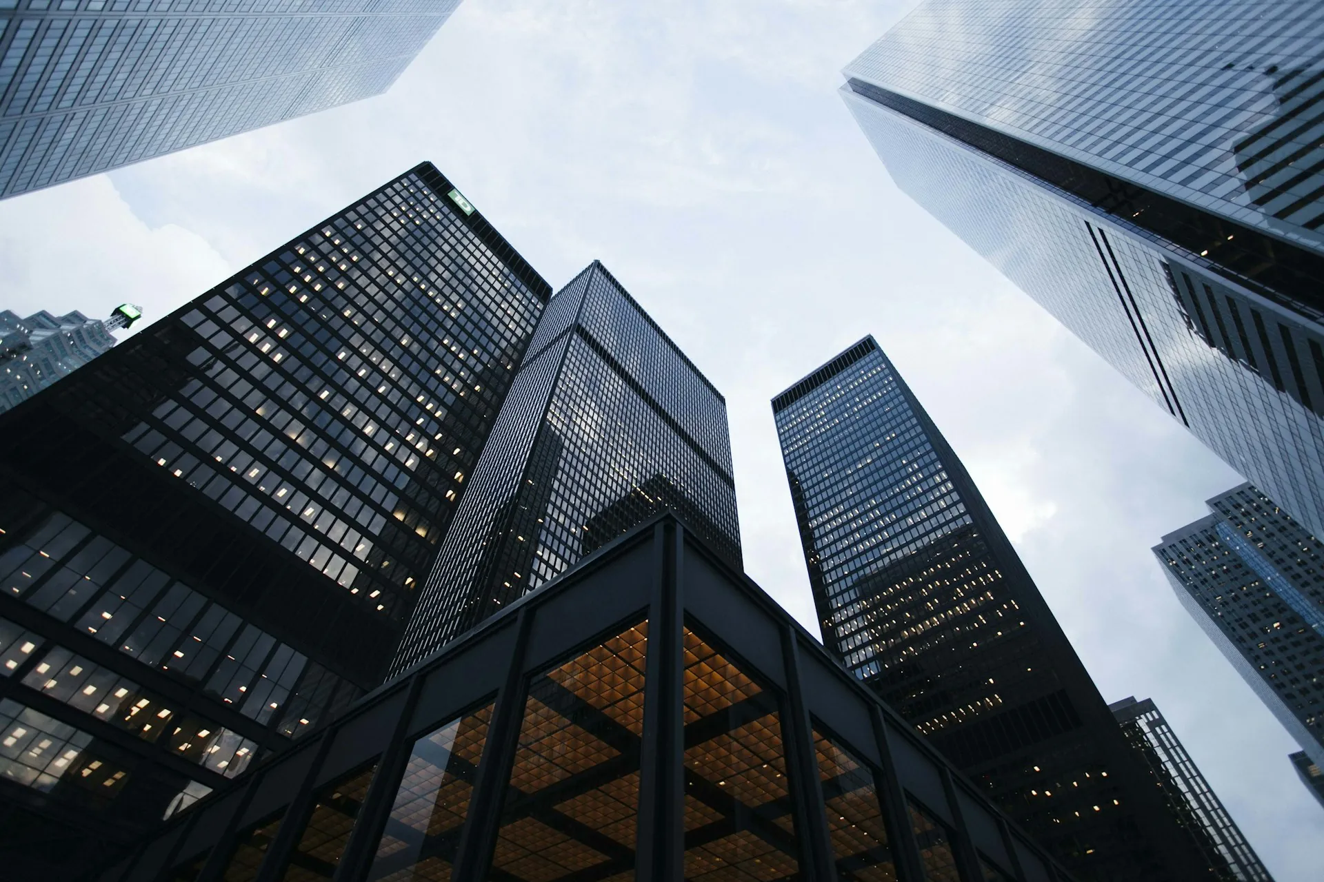 Glass skyscrapers seen from street level, rising into a grey sky