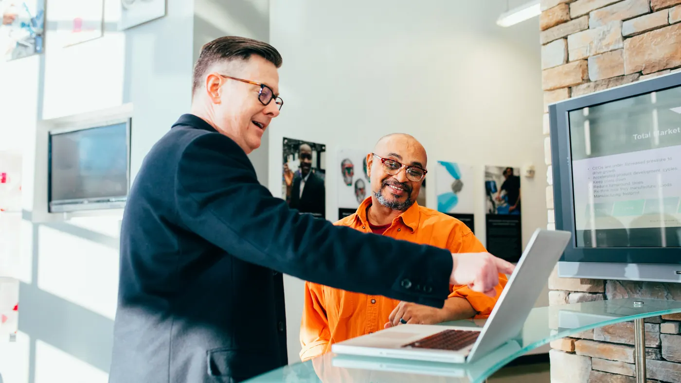Two colleagues at a counter going through figures together on a laptop