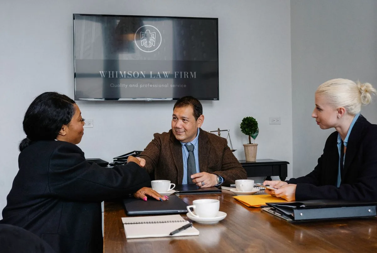 Colleagues shaking hands across a table in a law office