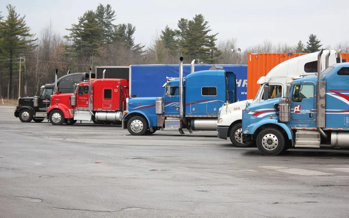 A line of semi trucks parked in a carrier yard