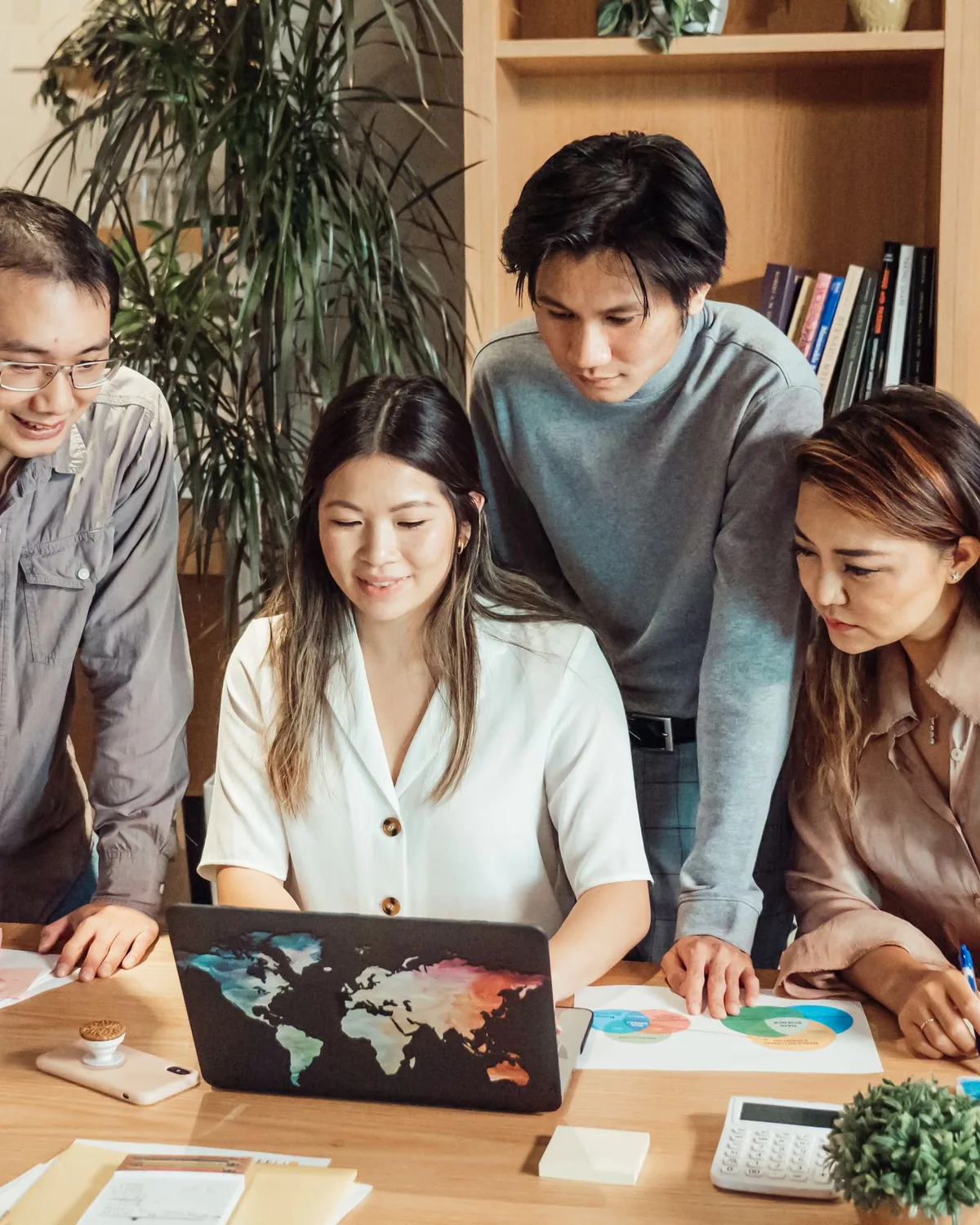 A leadership team reviewing portfolio figures around a laptop