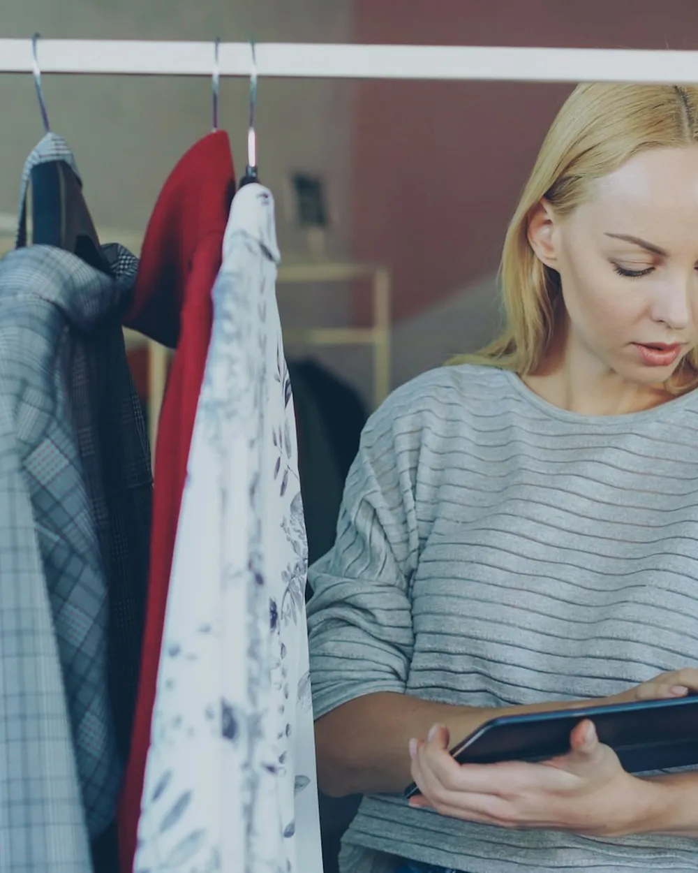 A retail buyer checking garments against a tablet on the shop floor