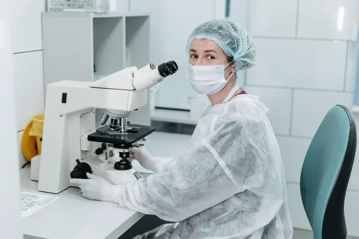 A scientist working with a microscope in a sterile lab