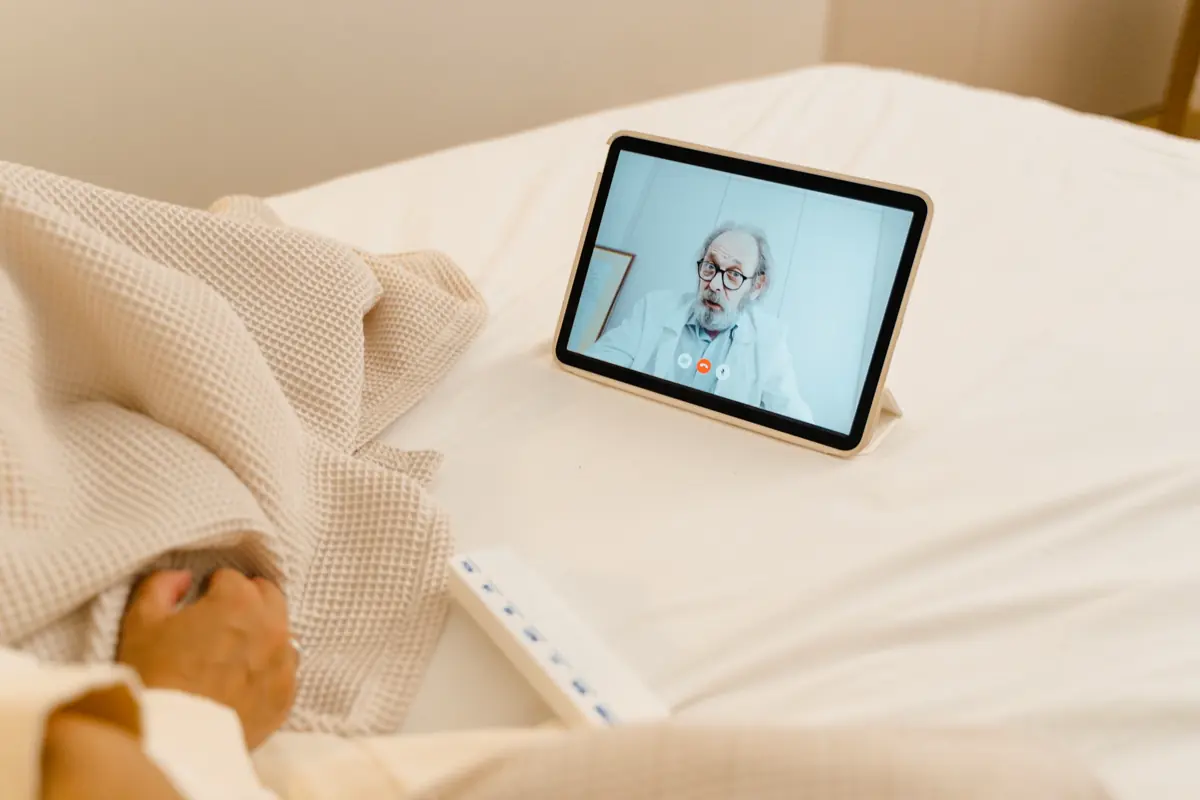 A patient in bed consulting a doctor over a tablet