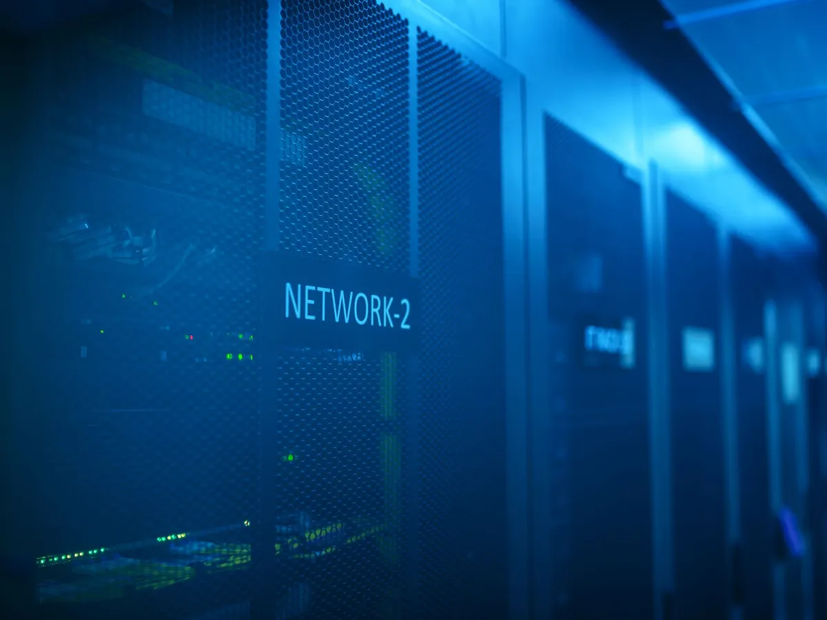 Server racks lit in blue inside a data centre aisle