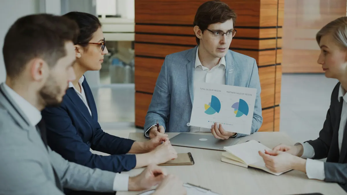 Consultant presenting pie charts to a business team in a meeting room