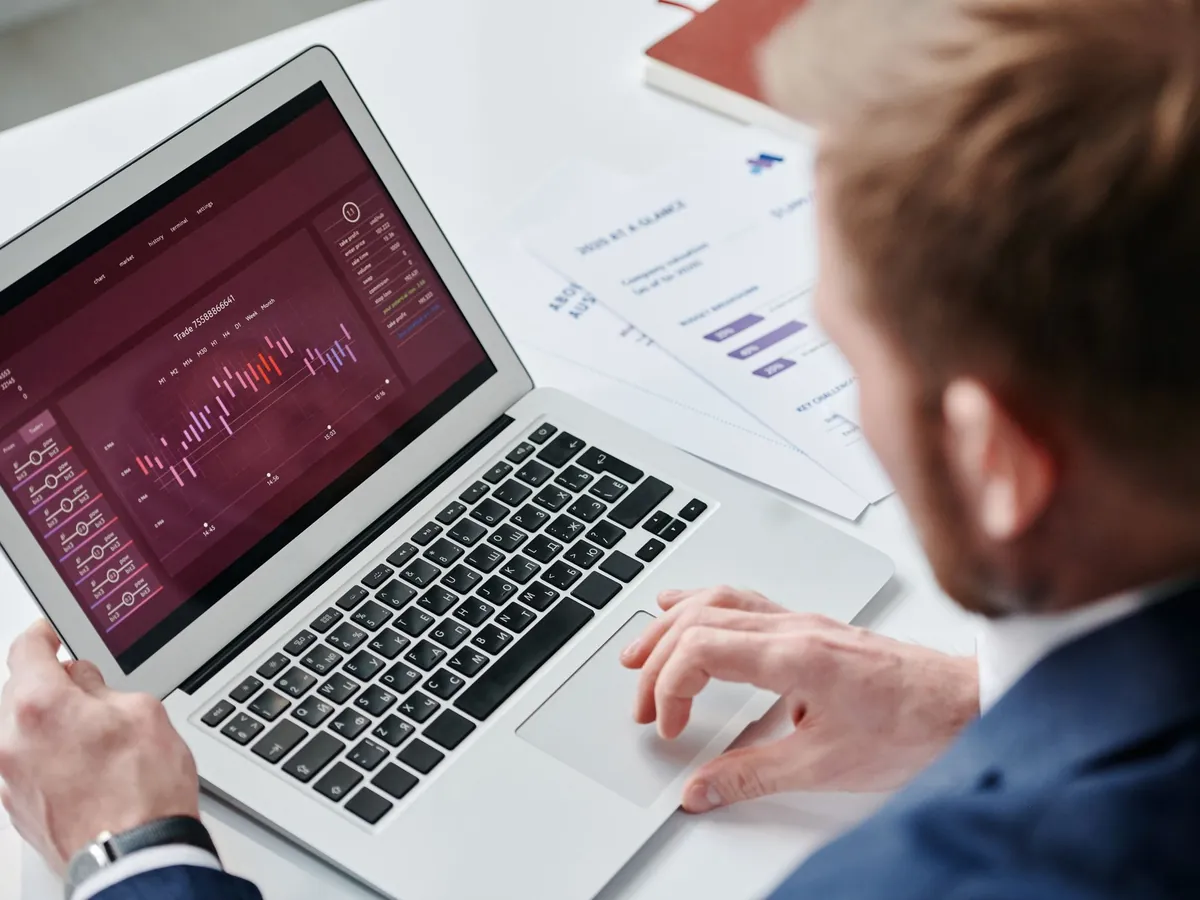 An analyst reviewing code and performance charts on a laptop