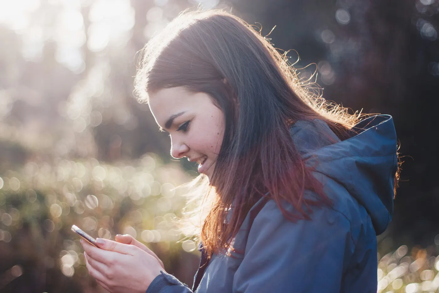 Woman smiling while chatting on her phone outdoors
