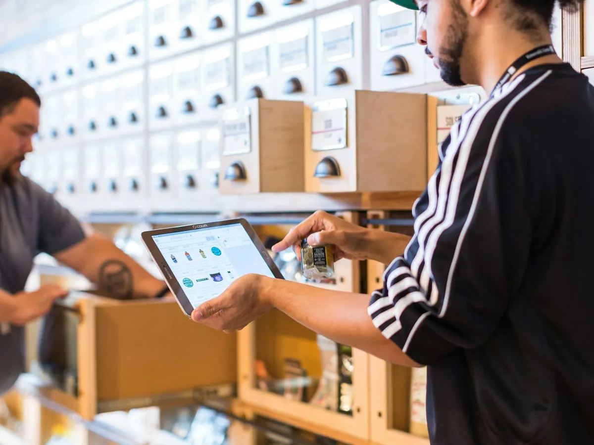 Two colleagues reviewing stock on a tablet inside a store stockroom