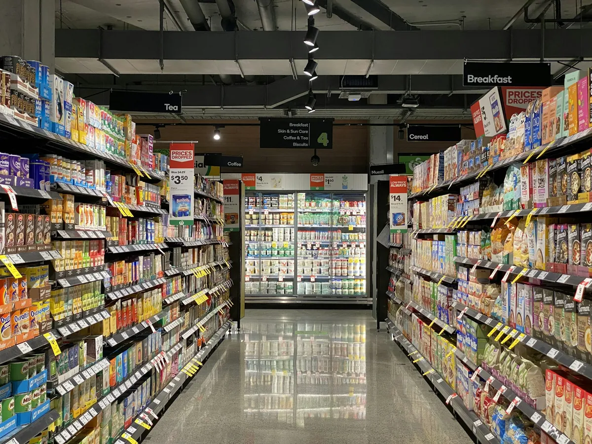 A long supermarket aisle stocked with packaged goods on both sides
