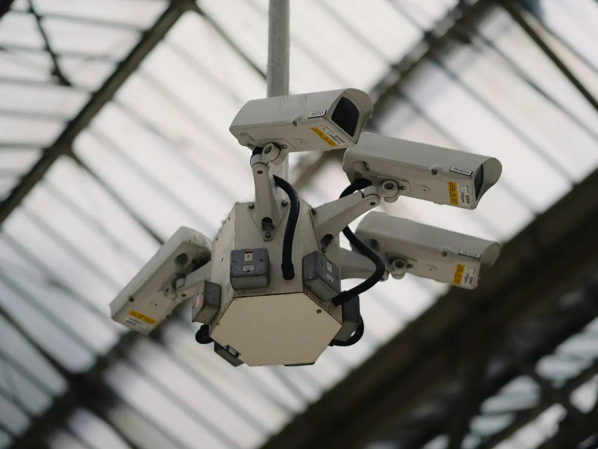 A cluster of surveillance cameras mounted under a glass roof