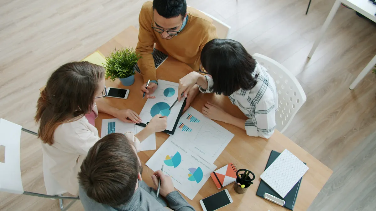 Team working together over printed charts at a wooden table
